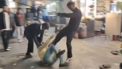 The image displays a picture of two men kicking a man in yellow shirt in Nanital