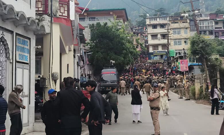 The image displays a picture of Nainital with police and a large number of right-wing protestors