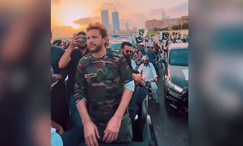The image displays a picture of former cricketer Shahid Afridi participating in a 'victory' rally in Karachi