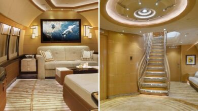 Luxurious interior of a customised Boeing 747-8 jet featuring a private lounge with a widescreen TV, plush seating, and a grand staircase with ambient lighting.
