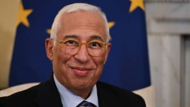 An older man with glasses and a tie smiling