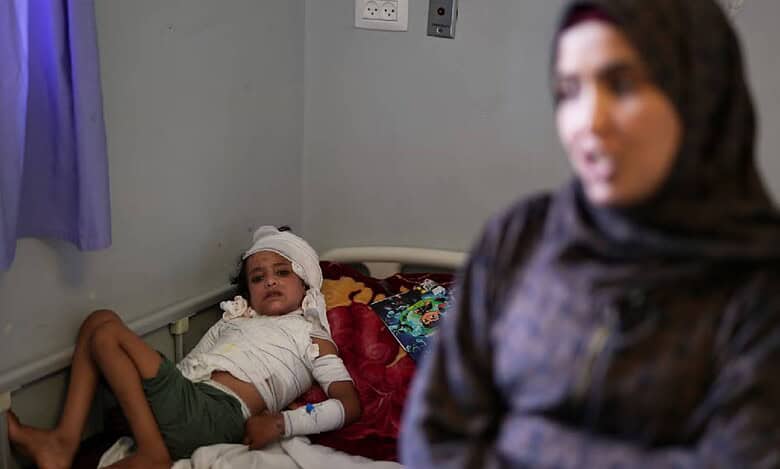 A young burns patient in Gaza lies in bed as his mother applies ointment to his injured body, carefully tending to his wounds.