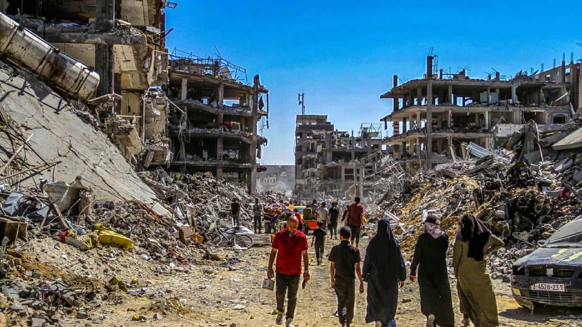 Civilians walk through rubble and destroyed buildings in Gaza after Israeli airstrikes, showing the humanitarian impact and devastation of conflict.