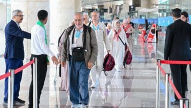 A group of Haj pilgrims arriving at an international airport, warmly welcomed by officials.