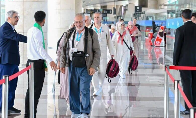A group of Haj pilgrims arriving at an international airport, warmly welcomed by officials.