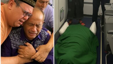 A grieving Indonesian man is consoled aboard a Saudi Arabian Airlines flight after his wife, a Haj pilgrim, died unexpectedly en route to Madinah. The deceased is respectfully covered in a green cloth and laid on the aircraft floor near the exit. Two men, including one in official uniform, stand in mourning.