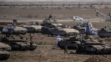 Israeli tanks with national flags positioned near Gaza border during ongoing military operations.