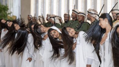 Emirati girls in white gowns perform the traditional Khaleeji dance by rhythmically flipping their hair in unison, as part of a ceremonial welcome for U.S. President Donald Trump in Abu Dhabi. Men in traditional dress stand behind them holding swords.