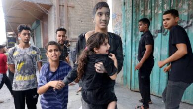 Dust-covered Palestinian children in Gaza walk through a bombed street after an Israeli airstrike, one carrying a terrified young girl to safety.