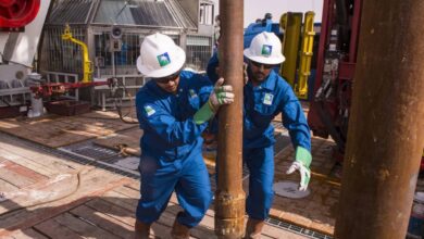 Saudi Aramco workers operate drilling equipment at an oil rig site.