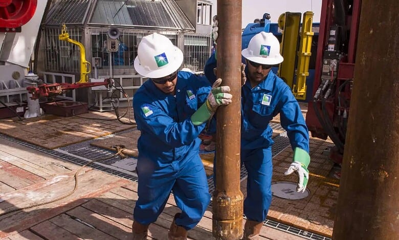 Saudi Aramco workers operate drilling equipment at an oil rig site.