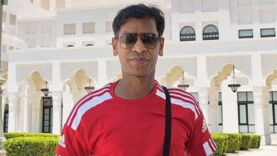 Venkata Giribabu Vulla, Qatar-based Indian Big Ticket winner, stands in front of white building in red Adidas shirt and sunglasses.