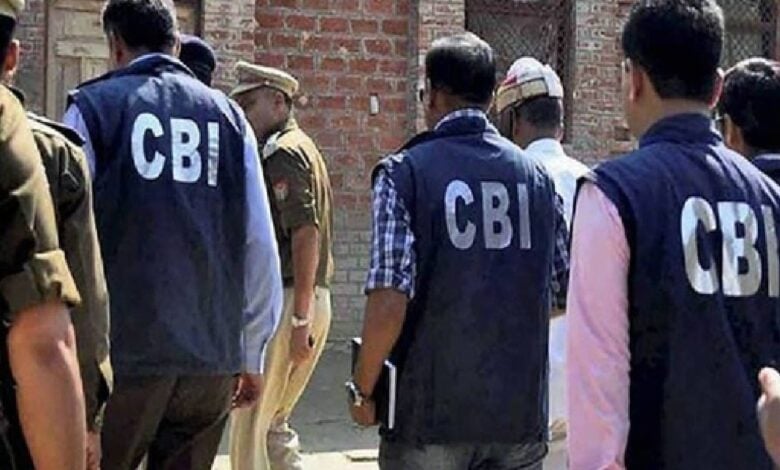The image of a CBI officers, wearing jackets marked "CBI", are seen entering a premises accompanied by local police personnel during an official investigation.