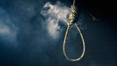 The image of a noose made of thick rope hangs against a dark, smoky background, symbolizing execution or death.