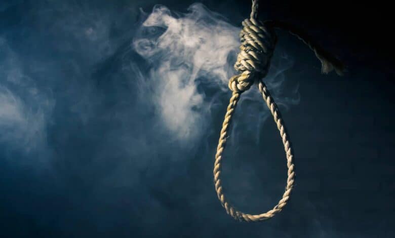 The image of a noose made of thick rope hangs against a dark, smoky background, symbolizing execution or death.