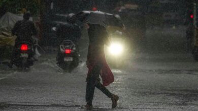 Woman with an umbrella walks through a water logged road for a story about IMD issuing a yellow alert for rain in Hyderabad