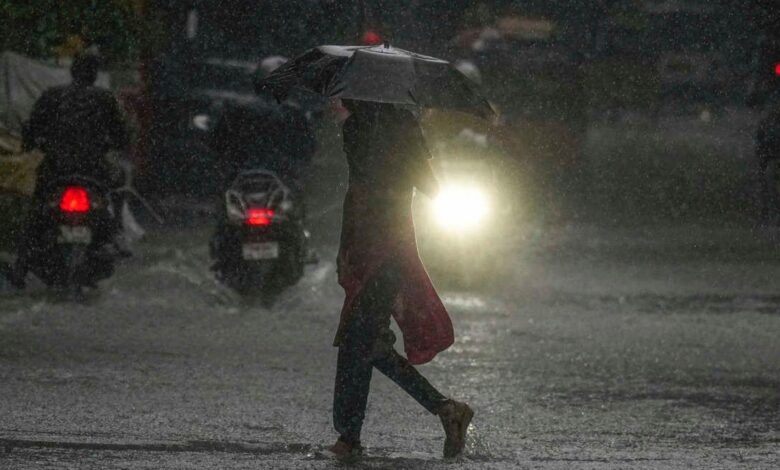 Woman with an umbrella walks through a water logged road for a story about IMD issuing a yellow alert for rain in Hyderabad