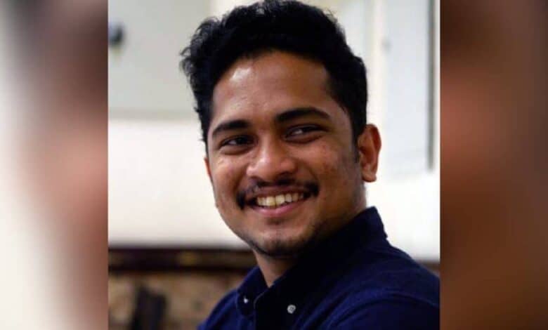 The image of 29-year-old Issac Paul Olakkengil, smiling and wearing a dark blue shirt, seated indoors.