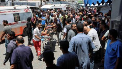 Palestinians rush a wounded person on a stretcher through a crowded area outside a hospital in Gaza after an Israeli airstrike.
