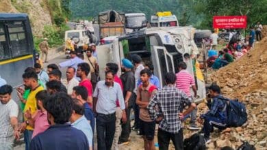 People wait at a roadside after a landslide occurred in Uttarakhan