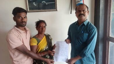 The image of a Lasmanna's family members handing over a written petition to Swadesh Parikipandla (right), a member of the Telangana State NRI Advisory Committee, seeking help to bring Lasmanna back from Dubai. They are standing indoors, holding the document together.