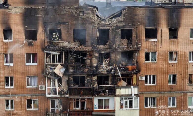 The image displays a picture of a burnt building in Ukraine's Kharkiv city