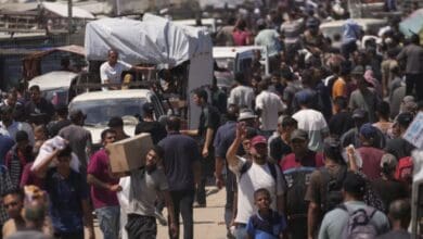 Palestinians carry bags containing food and humanitarian aid packages delivered by the Gaza Humanitarian Foundation in southern Gaza Strip on Sunday