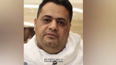 Amer al-Gaddafi, a Libyan pilgrim, smiling while seated, wearing white Ihram clothes during Haj in Makkah.