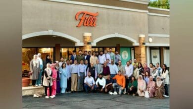 A large group of men and women pose together outside FiLLi Cafe in Villa Park, Illinois, during the DAANA mentorship event. The café's exterior features the orange FiLLi sign above, with attendees dressed in a mix of formal and semi-formal attire.