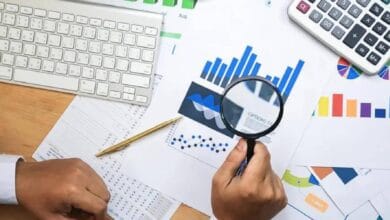 Representative image of financial data analysis with charts and magnifying glass.