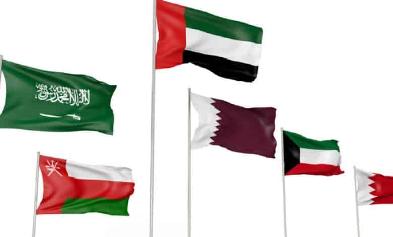 Six national flags of Gulf Cooperation Council (GCC) countries—Saudi Arabia, UAE, Qatar, Kuwait, Oman, and Bahrain—waving on flagpoles against a white background.