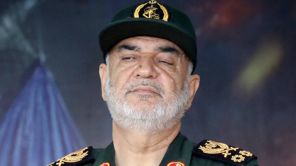 The image shows Iran’s Revolutionary Guard chief Gen Hossein Salami in uniform, wearing a cap with the Guard’s emblem, looking solemn.