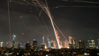 A night-time scene showing fiery explosions and smoke rising over a city skyline, as Iran launches strikes on Israel late Friday night, June 13.