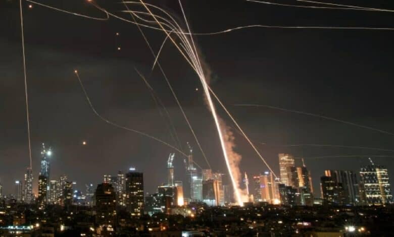 A night-time scene showing fiery explosions and smoke rising over a city skyline, as Iran launches strikes on Israel late Friday night, June 13.