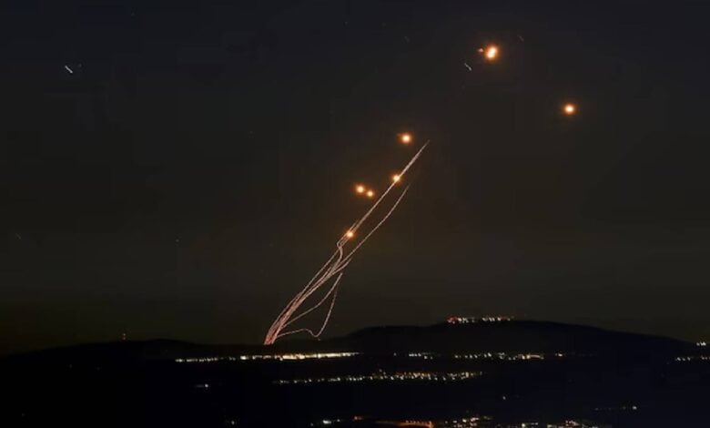 Israel’s Iron Dome missile defence system launches an interceptor during an incoming rocket attack, with smoke trails visible against the evening sky.
