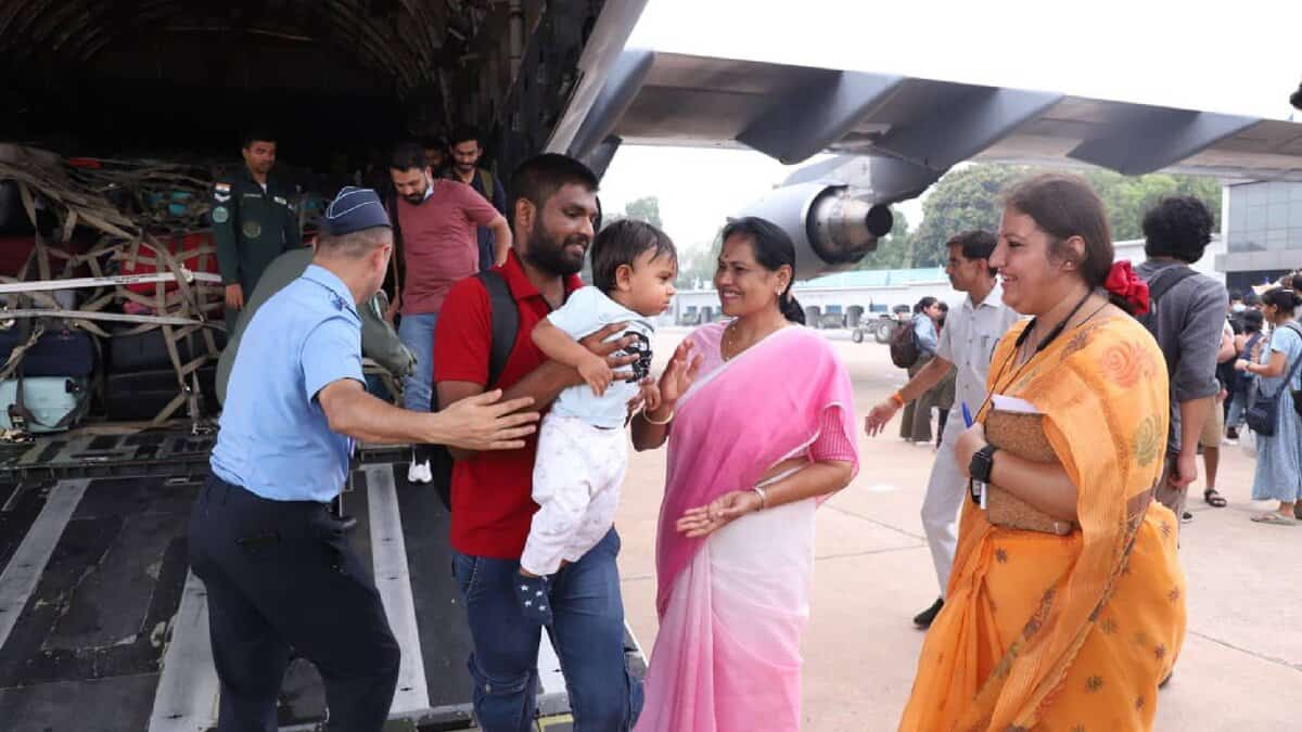 Minister Shobha Karandlaje welcomes Indian evacuees, including a man holding a child, arriving from Israel on an IAF aircraft under Operation Sindhu.