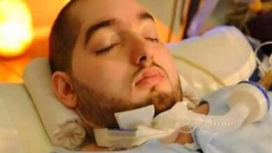 The image of a Prince Al-Waleed bin Khaled bin Talal, known as the Sleeping Prince, lies in a hospital bed with his eyes closed, supported by a ventilator tube attached at his neck.