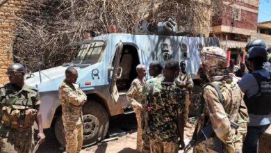 Sudanese army soldiers stand near a damaged armoured vehicle after clashes with the Rapid Support Forces (RSF) in Khartoum.