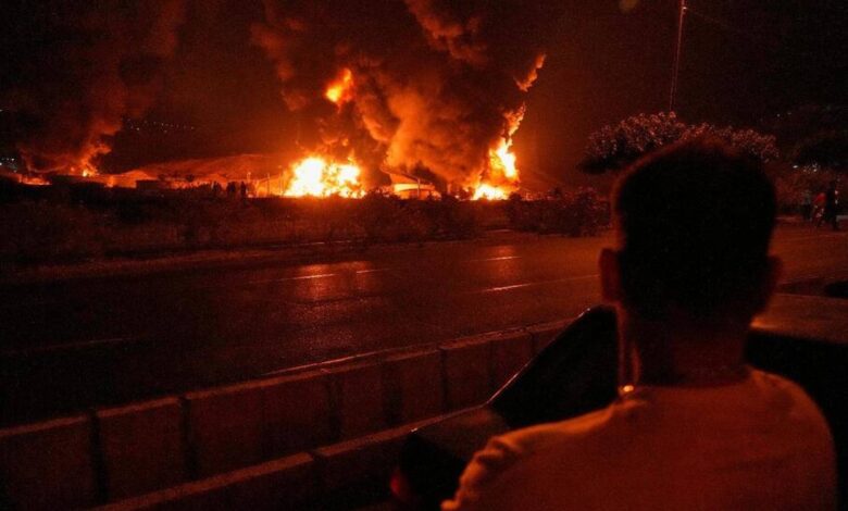 The image of a man watches massive flames and thick smoke rise from an oil storage facility in Tehran after it was struck by an Israeli missile early on June 15.
