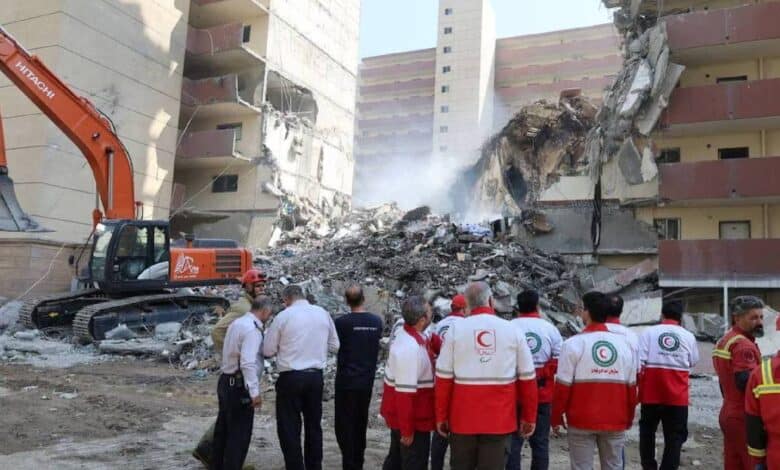 Rescuers search through debris at the site of a damaged building following Israeli strikes in Tehran, Iran, on June 13, 2025. The building shows severe structural damage, with rubble scattered around as emergency workers assess the scene.