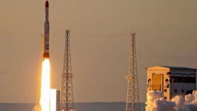 A rocket launches into the sky from a desert space facility at sunset, emitting flames and smoke – representative image.