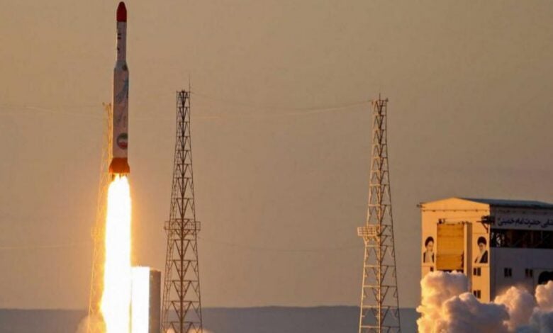 A rocket launches into the sky from a desert space facility at sunset, emitting flames and smoke – representative image.