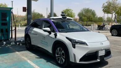 A self-driving electric taxi with TGA and Uber logos parked at a charging station in Riyadh during Saudi Arabia’s pilot launch.