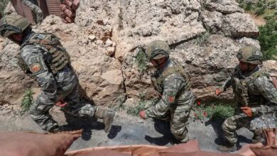 The image of Turkish soldiers in combat gear patrol a rocky terrain near a military outpost, demonstrating operational readiness in a mountainous border region.