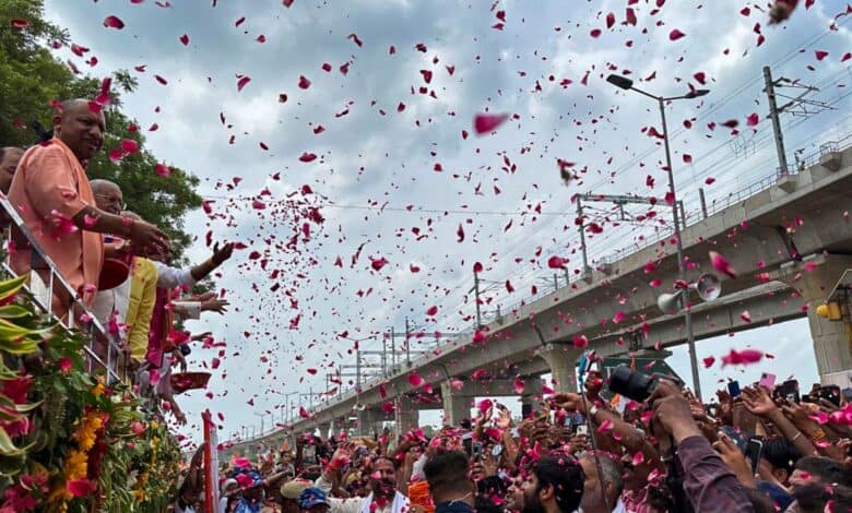 Uttar Pradesh Chief Minister Yogi Adityanath showers flower petals on 'Kanwariyas' during their pilgrimage in the holy month of 'Shravan' in Meerut on Sunday. (PTI Photo)