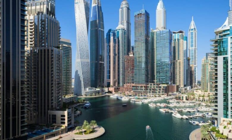 Dubai Marina skyline with modern high-rise buildings and yachts docked along the waterfront.