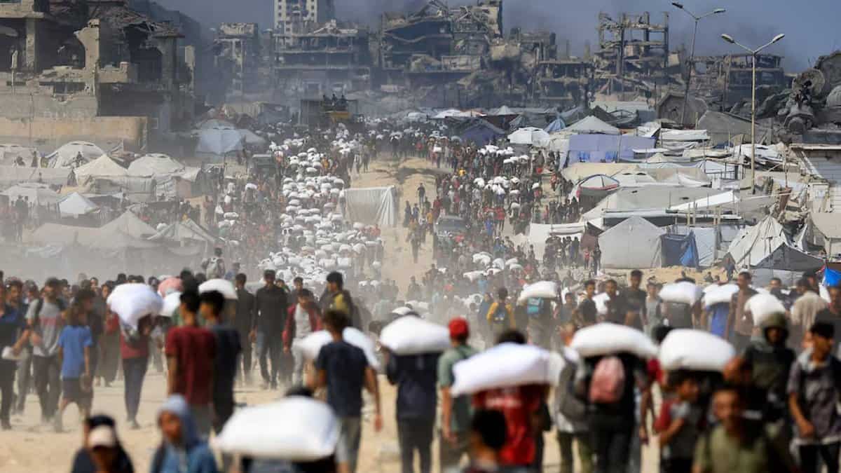 Palestinians carry aid packages through a crowded street in Beit Lahia, northern Gaza, on July 20, 2025, amid a worsening hunger crisis.