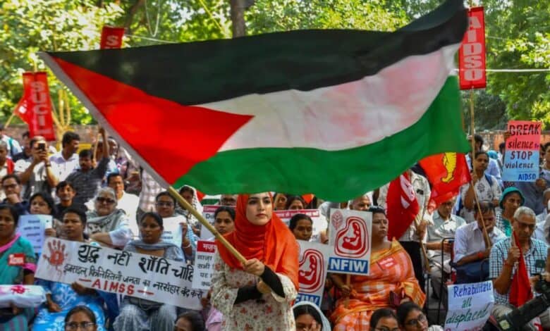 Woman waves Palestinian flag at Gaza ceasefire protest in New Delhi.