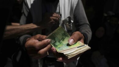 A Palestinian vegetable merchant holds worn-out Israeli banknotes in Gaza City on July 9, 2025, highlighting the cash crisis affecting daily trade in the war-torn territory.