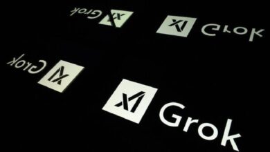 The logo of Elon Musk's AI chatbot Grok is seen reflected on a dark surface.